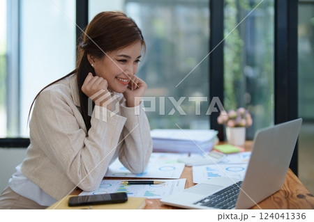 Confident business woman smiling Show successful gestures at her desk with market charts and documents in office 124041336
