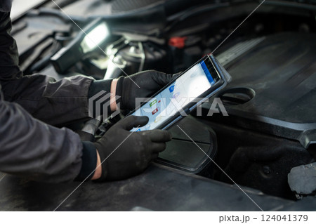 Serviceman with tablet checks car software in car service 124041379