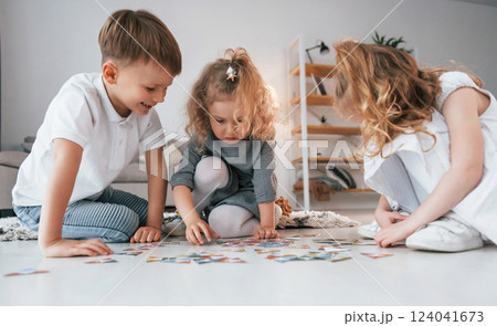 Sitting on the floor and playing game. Group of children is together at home at daytime 124041673