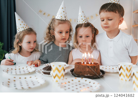 Sweet cake is on the table. Celebrating brithday. Group of children is together at home at daytime 124041682