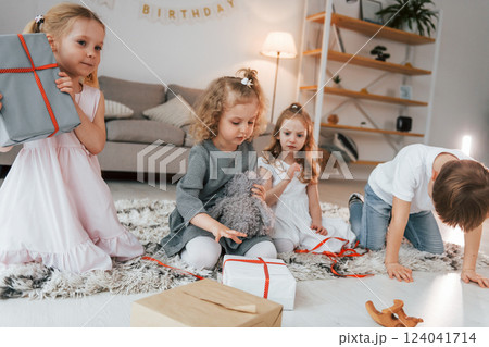 With gift boxes. Celebration birthday. Group of children is together at home at daytime With gift boxes. Celebration birthday. Group of children is together at home at daytime 124041714