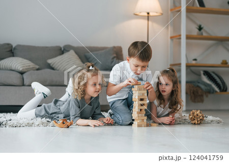 Playing wooden tower game. Group of children is together at home at daytime 124041759