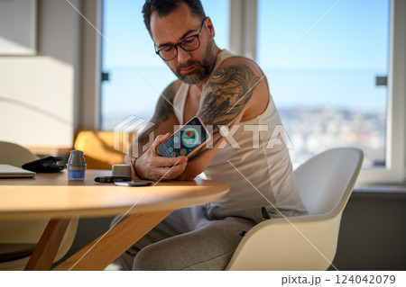 Man with CGM sensor is checking blood glucose level using smartphone app. 124042079