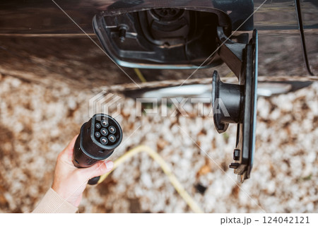 Man charging electric car, hodding charger in hand. Man charging electric car, hodding charger in hand. 124042121
