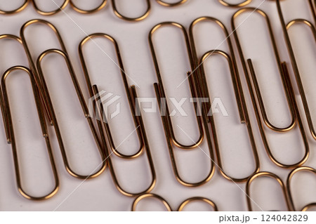 large sized copper paper clips lie on white blank paper large sized copper paper clips lie on white blank paper 124042829