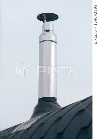 Galvanized metal chimney exhaust on asphalt roof with a rain cap Galvanized metal chimney exhaust on asphalt roof with a rain cap 124042895