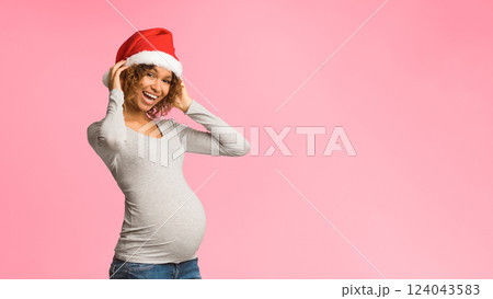 Excited pregnant woman in Santa hat posing over grey background, panorama with free space Excited pregnant woman in Santa hat posing over grey background, panorama with free space 124043583