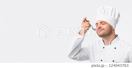 Delicious Food. Satisfied Chef Tasting Food Holding Spoon Standing Over White Background. Studio Shot, Empty Space. 124043763