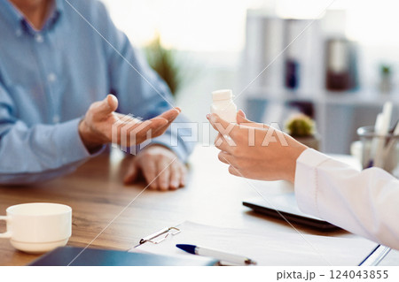 Medicine Concept. Close up of doctor giving medication pill bottle to retired man, copy space Medicine Concept. Close up of doctor giving medication pill bottle to retired man, copy space 124043855