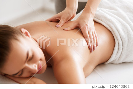 Young girl receiving back massage with closed eyes in spa center, closeup 124043862