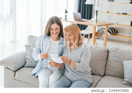 Looking at old photos. Mother and daughter is together at home 124043880
