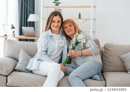 With flowers in hands. Happy mother's day. Senior woman and daughter is together at home With flowers in hands. Happy mother's day. Senior woman and daughter is together at home 124043905