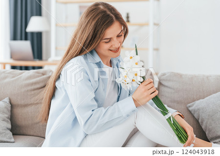 Beautiful white flowers in hands. Young beautiful woman is home alone in domestic room 124043918