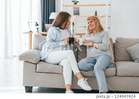 With cup of drinks, having a conversation. Mother and daughter is together at home 124043924