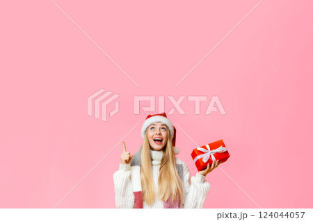 Time to buy christmas gifts. Excited girl in santa hat with gift box pointing at copy space Time to buy christmas gifts. Excited girl in santa hat with gift box pointing at copy space 124044057