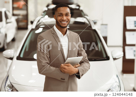 Smiling Car Dealer Standing Near Luxury Automobile Holding Folder Working In Auto Selling Showroom. Vehicle Dealership Concept Smiling Car Dealer Standing Near Luxury Automobile Holding Folder Working In Auto Selling Showroom. Vehicle Dealership Concept 124044148