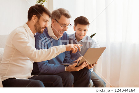 Grandfather Learning To Use Laptop Computer With Adult Son And Grandson Sitting On Sofa Indoor. Selective Focus 124044164