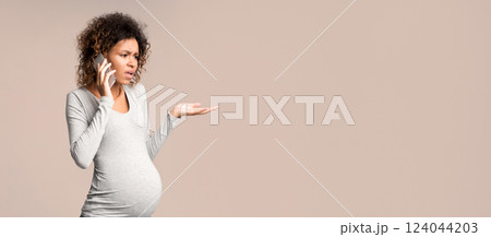 Worried afro pregnant woman talking on phone, having serious conversation, grey background 124044203
