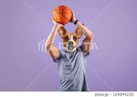 A man with a dog's head is holding a basketball above his head. He is wearing a gray t-shirt and is standing against a purple background. A man with a dog's head is holding a basketball above his head. He is wearing a gray t-shirt and is standing against a purple background. 124044220