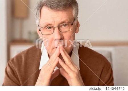 Portrait Of Serious Senior Man Thinking About Retired Life Holding Hands Near Face Sitting On Sofa Indoor. Selective Focus 124044242