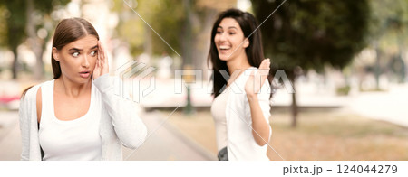 Unwanted encounter. Happy girl greeting waving hand and friend ignoring her in park Unwanted encounter. Happy girl greeting waving hand and friend ignoring her in park 124044279