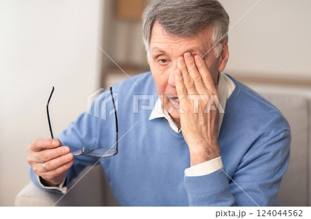 Glaucoma. Tired Elderly Man Massaging Eye Holding Eyeglasses Having Eyestrain And Ocular Tension Sitting On Couch At Home. Selective Focus 124044562