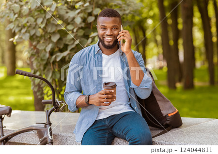 African American Man Employee Drinking Coffee In Park And Talking On Cellphone, Relaxing Outdoors During Break At Work 124044811