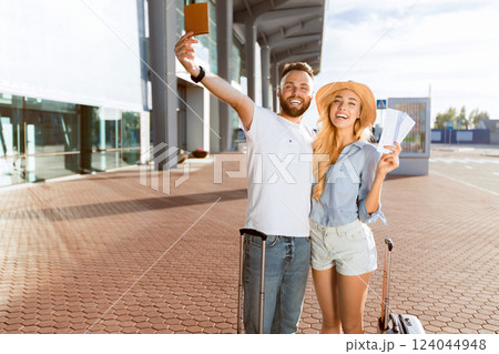 Travel concept. Loving couple going on vacation and holding tickets against airport building Travel concept. Loving couple going on vacation and holding tickets against airport building 124044948
