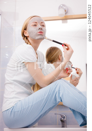 Woman applying with brush clay mud mask to her face Woman applying with brush clay mud mask to her face 124045522