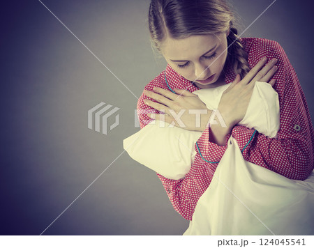 Sad depressed girl in bed gripping pillow Sad depressed girl in bed gripping pillow 124045541