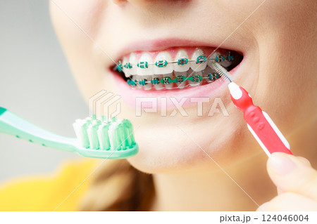 Girl with teeth braces using interdental and traditional brush 124046004