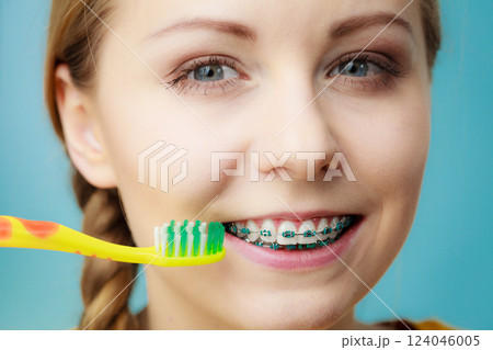 Woman with teeth braces using brush 124046005