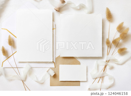 Cards and envelopes near silk ribbons and dried hare's tail grass top view on white, wedding mockup Cards and envelopes near silk ribbons and dried hare's tail grass top view on white, wedding mockup 124046158