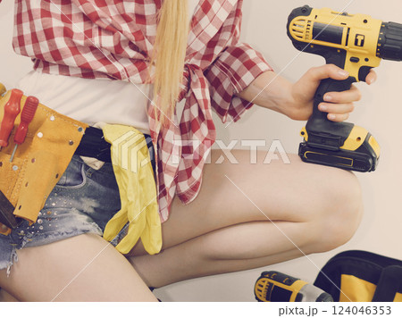 Woman wearing checked shirt and toolbelt 124046353
