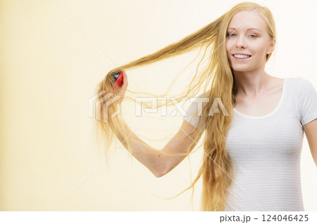 Blonde girl brushing her long hair Blonde girl brushing her long hair 124046425