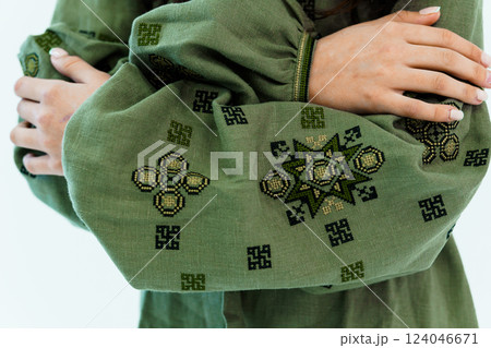 Close-up of Hands Embracing Green Fabric with Intricate Geometric Embroidery Designs Close-up of Hands Embracing Green Fabric with Intricate Geometric Embroidery Designs 124046671