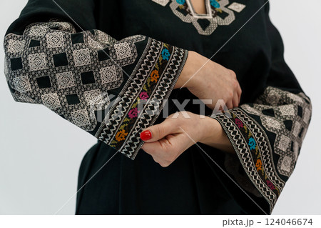 Close-up of Woman's Hands Adjusting Elegant Black Garment with Embroidered Traditional Pattern Sleeves Close-up of Woman's Hands Adjusting Elegant Black Garment with Embroidered Traditional Pattern Sleeves 124046674