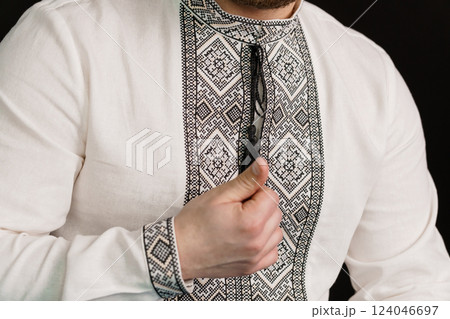 Close-Up of a Man in Traditional White Shirt with Intricate Black Geometric Embroidery Design 124046697