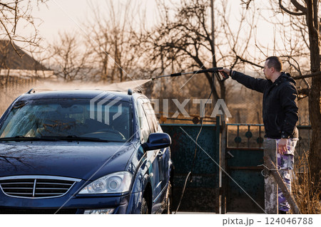 Man Washing Car Outdoors with High-Pressure Water Jet on Sunny Day 124046788