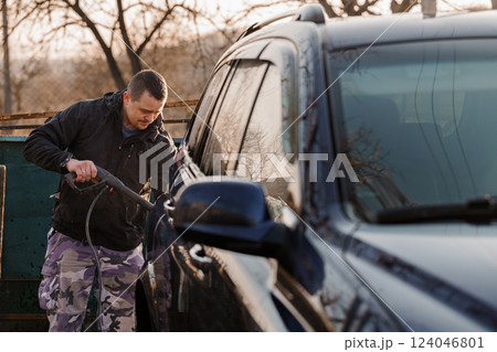Man Thoroughly Cleaning Vehicle Exterior Using Pressure Washer Outdoors Man Thoroughly Cleaning Vehicle Exterior Using Pressure Washer Outdoors 124046801