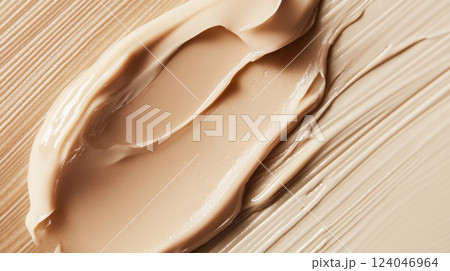 A creamy foundation swatch is artfully spread over a textured beige surface, highlighting its smooth consistency and natural hue. This visual captures the essence of makeup application techniques. A creamy foundation swatch is artfully spread over a textured beige surface, highlighting its smooth consistency and natural hue. This visual captures the essence of makeup application techniques. 124046964