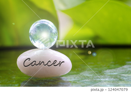 Cancer text engraved on Zen stone with shining glass marble on top. Zodiac concept 124047079