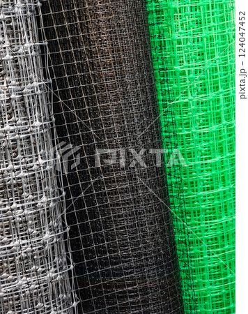 Rolls of wire mesh in various colors displayed together for construction and fencing purposes at a hardware store 124047452