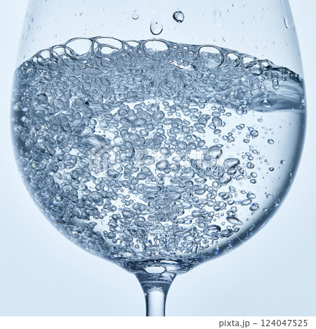 Close-up photo of water filled with bubbles in clear stemmed glass against soft background. Mock up. Close-up photo of water filled with bubbles in clear stemmed glass against soft background. Mock up. 124047525
