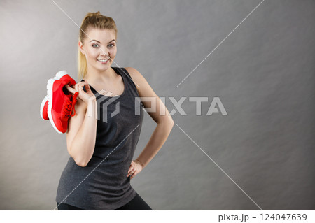 Happy woman presenting sportswear trainers shoes Happy woman presenting sportswear trainers shoes 124047639