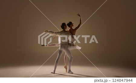 Ballet duet moves in perfect sync, ballerina extending with grace, partner supporting with strength, soft light emphasizing elegance. Ballet duet moves in perfect sync, ballerina extending with grace, partner supporting with strength, soft light emphasizing elegance. 124047944
