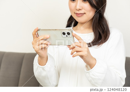 リビングで動画を見るアジア人女性01 124048120