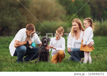 Sitting on the ground with dog. Family have weekend outdoors at summertime together Sitting on the ground with dog. Family have weekend outdoors at summertime together 124048372