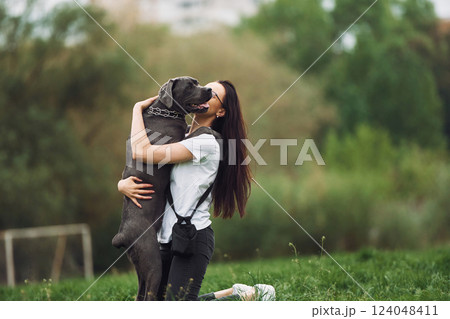 Hugs the pet. Young brunette is having a walk with her dog outdoors Hugs the pet. Young brunette is having a walk with her dog outdoors 124048411