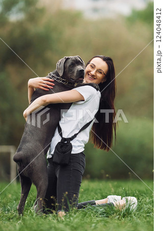 Hugs the pet. Young brunette is having a walk with her dog outdoors Hugs the pet. Young brunette is having a walk with her dog outdoors 124048412